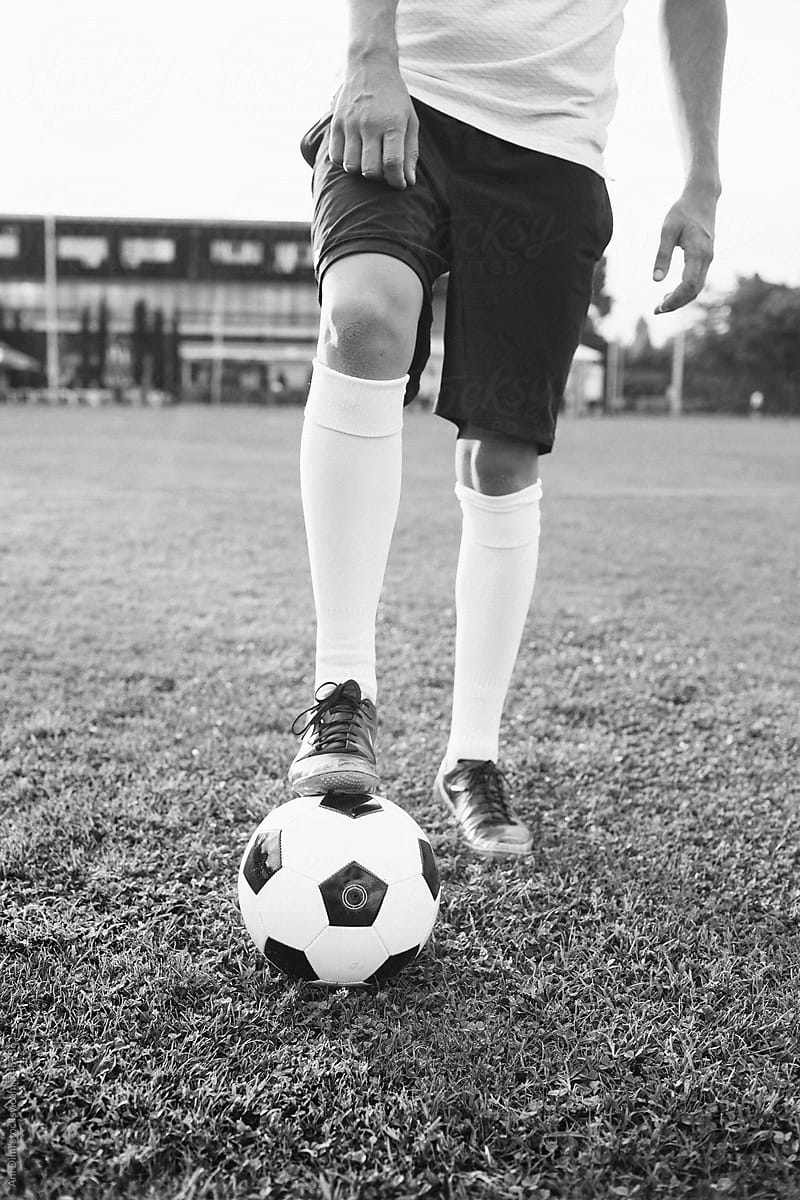 Boy in football boots and socks standing on soccer ball
