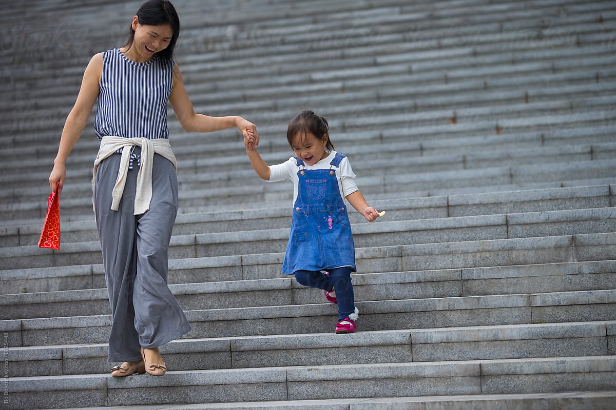 little girl jumping on steps with her mother