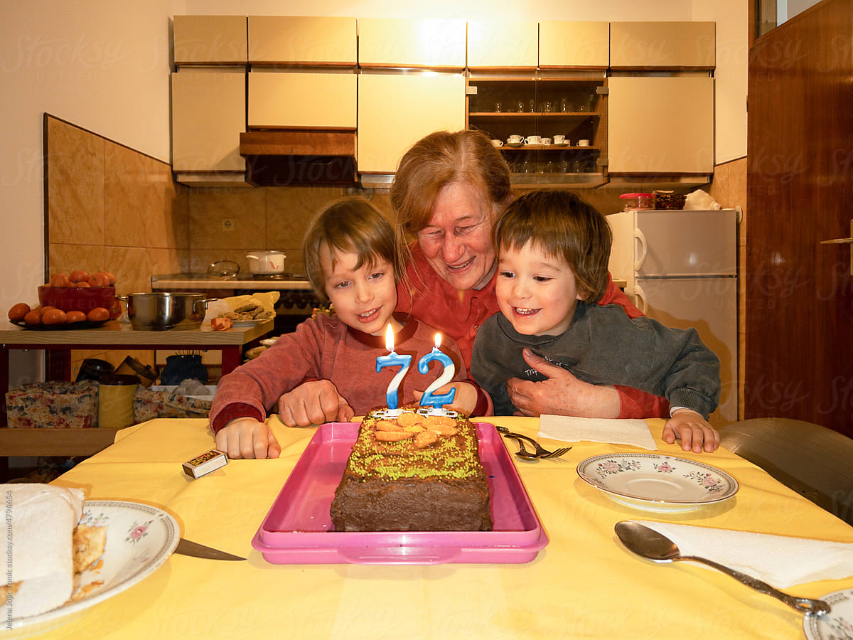 Grandmother with her grandchildren blowing candles