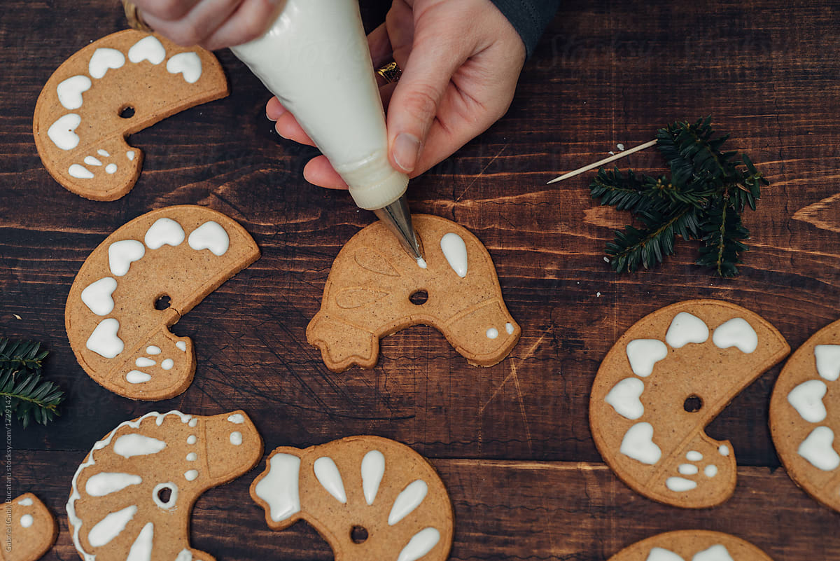 Woman's hands decorating bird-shaped gingerbread cookies