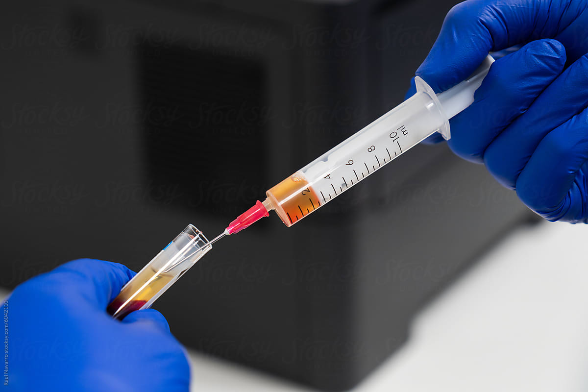 Laboratory technician drawing blood into syringe