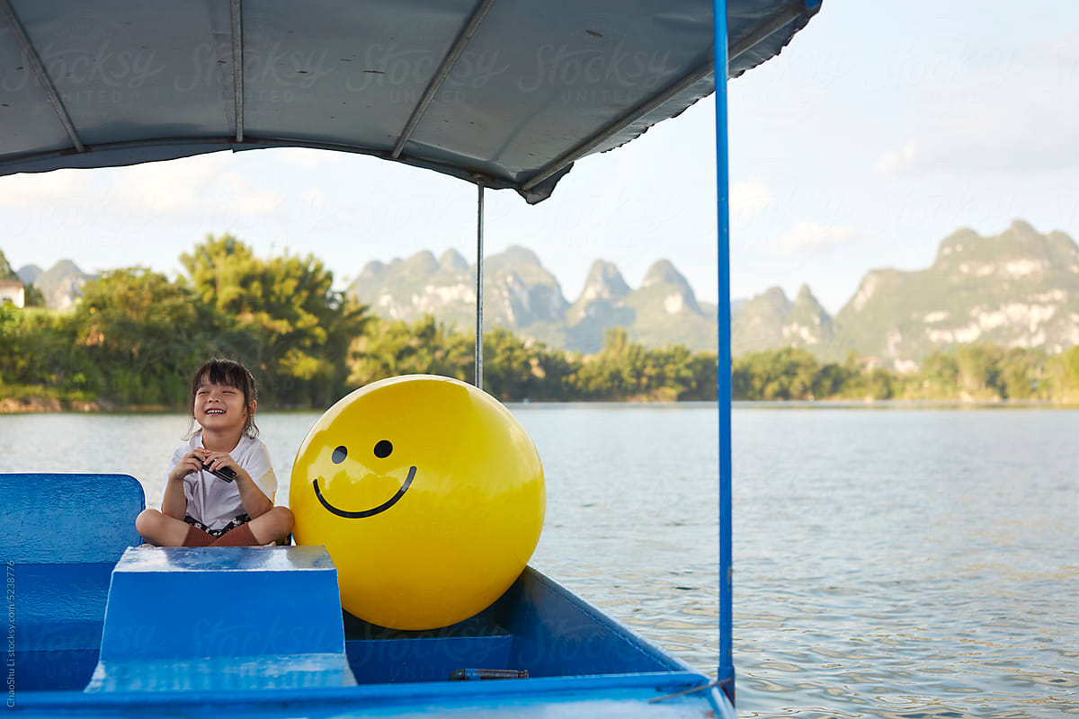 Asian girl having fun on a river cruise with her mood balloons