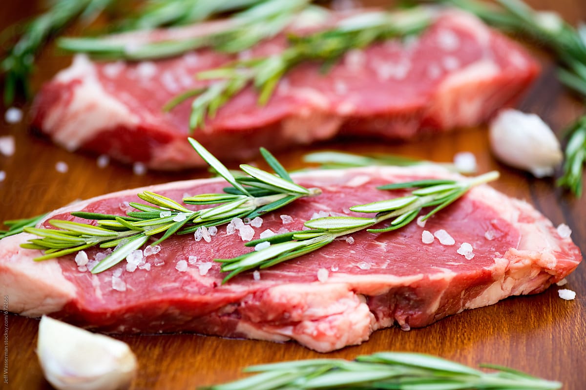Raw Sirloin Steaks with Rosemary on Board