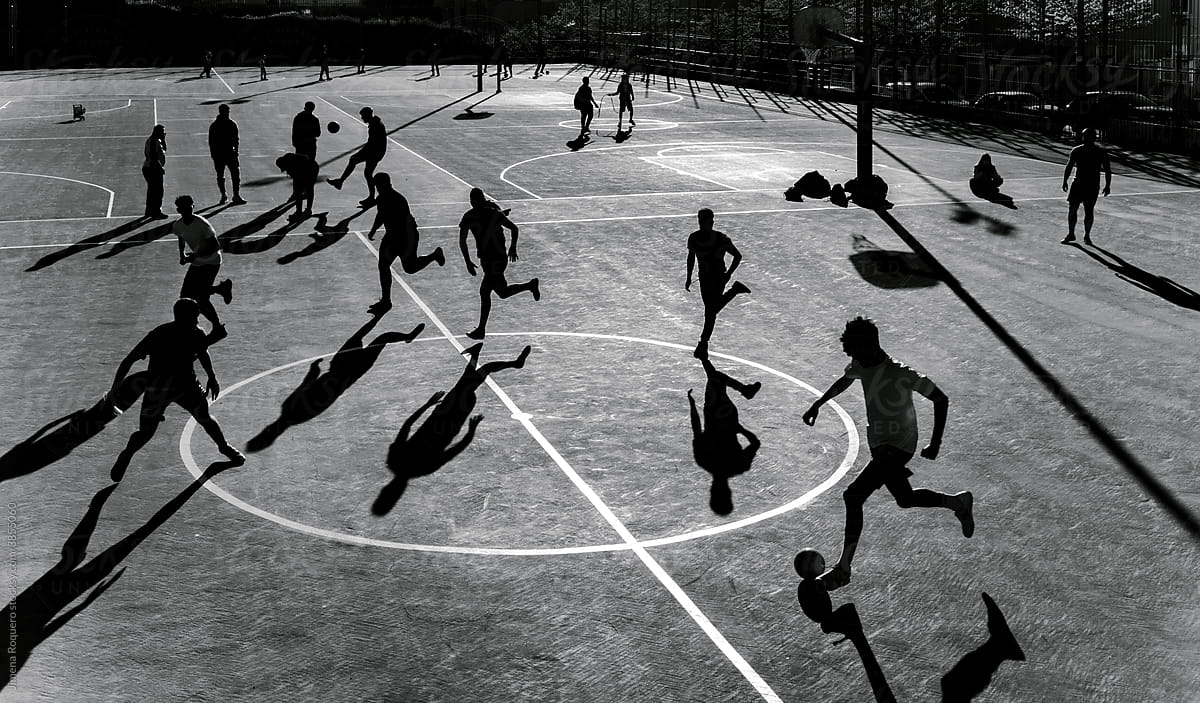 Anonymous group of young people playing soccer outdoors at sunset