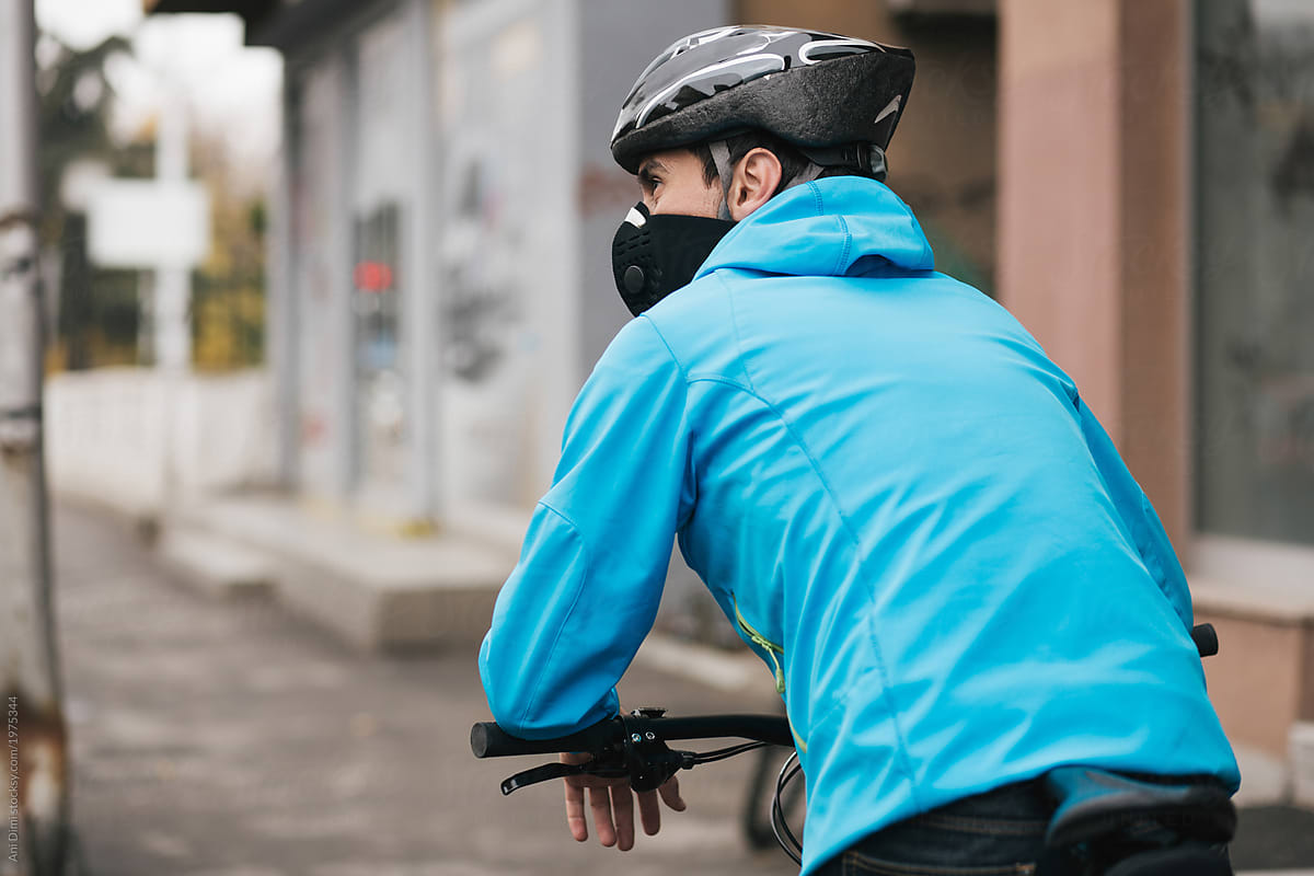 Young guy with face mask riding bike in the street
