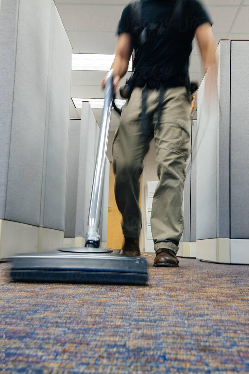 After hours janitor vacuums carpets in an office building
