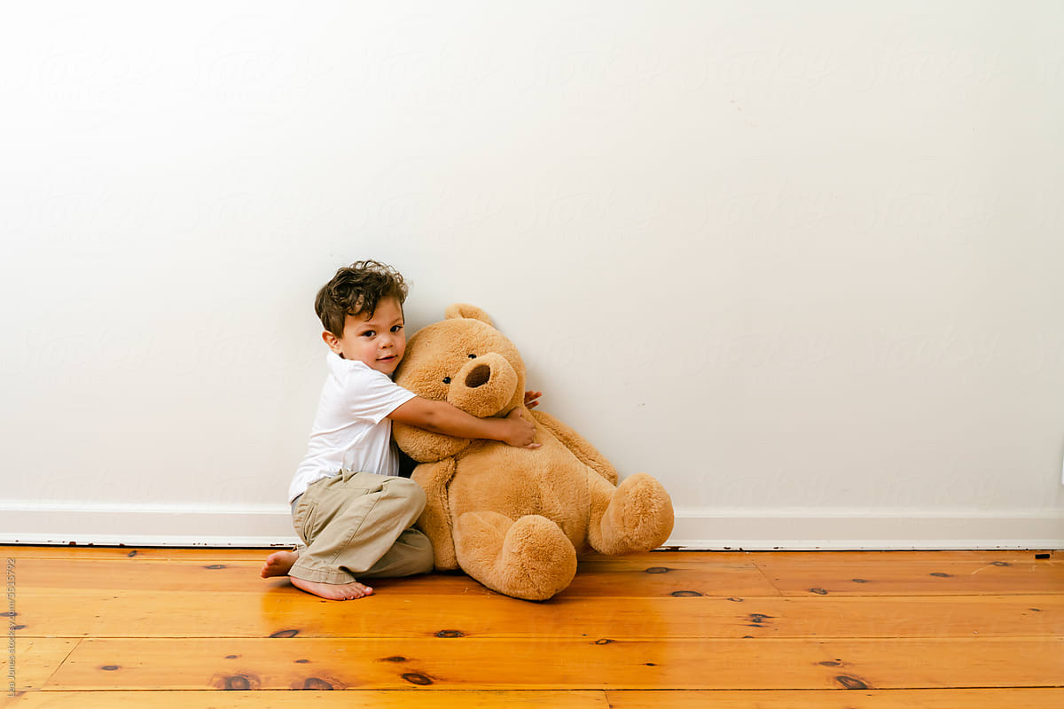 little boy playing with big teddy bear