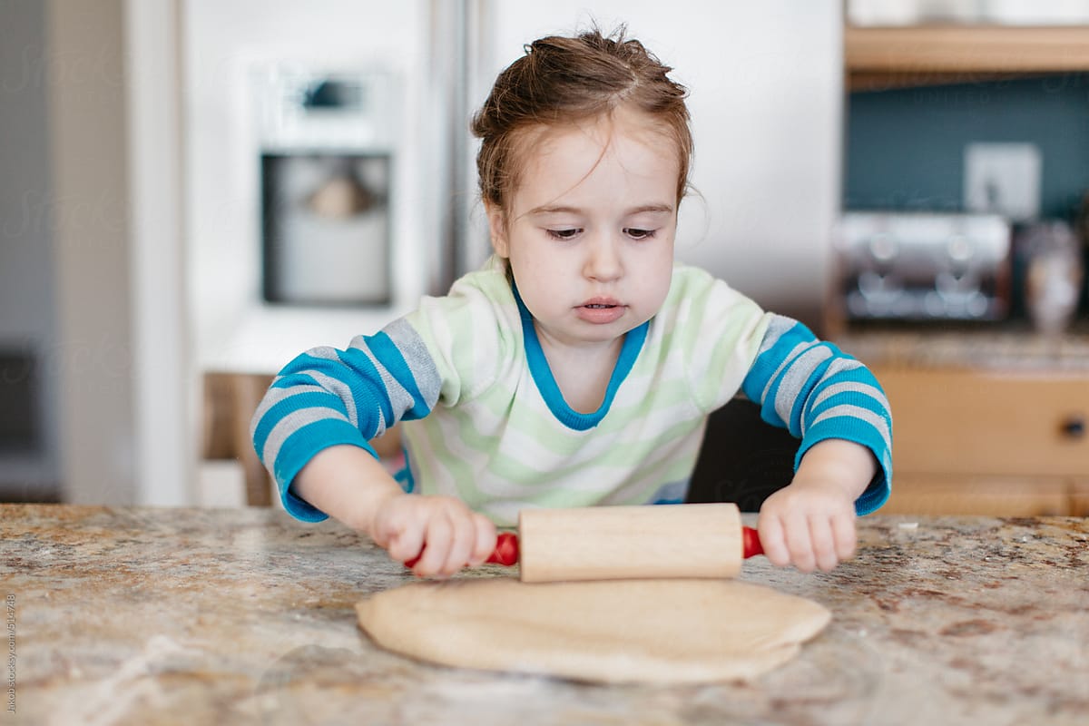 Toddler rolling dough with a rolling pin