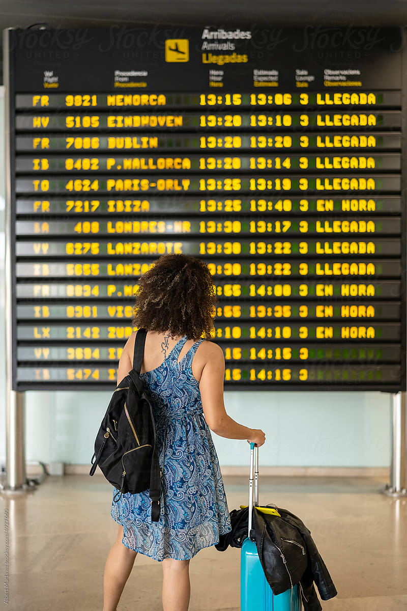 Traveling woman in airport terminal with timetable