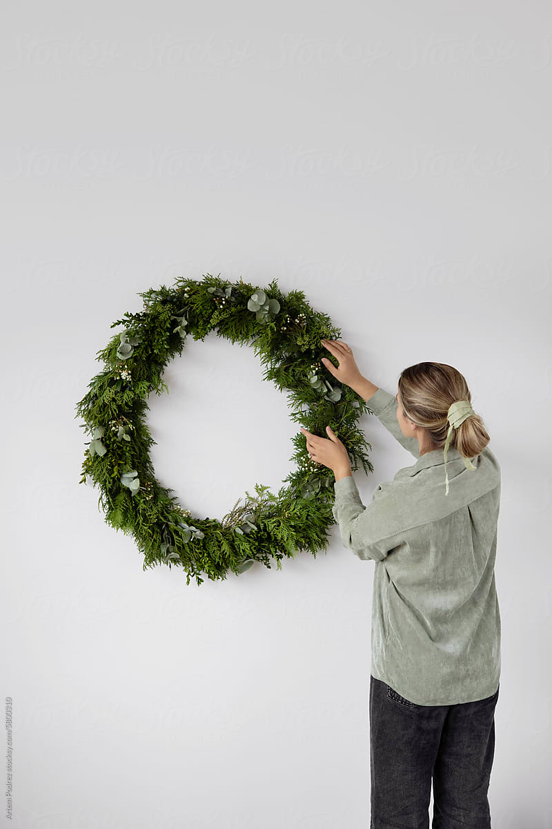 A woman decorates a Christmas wreath