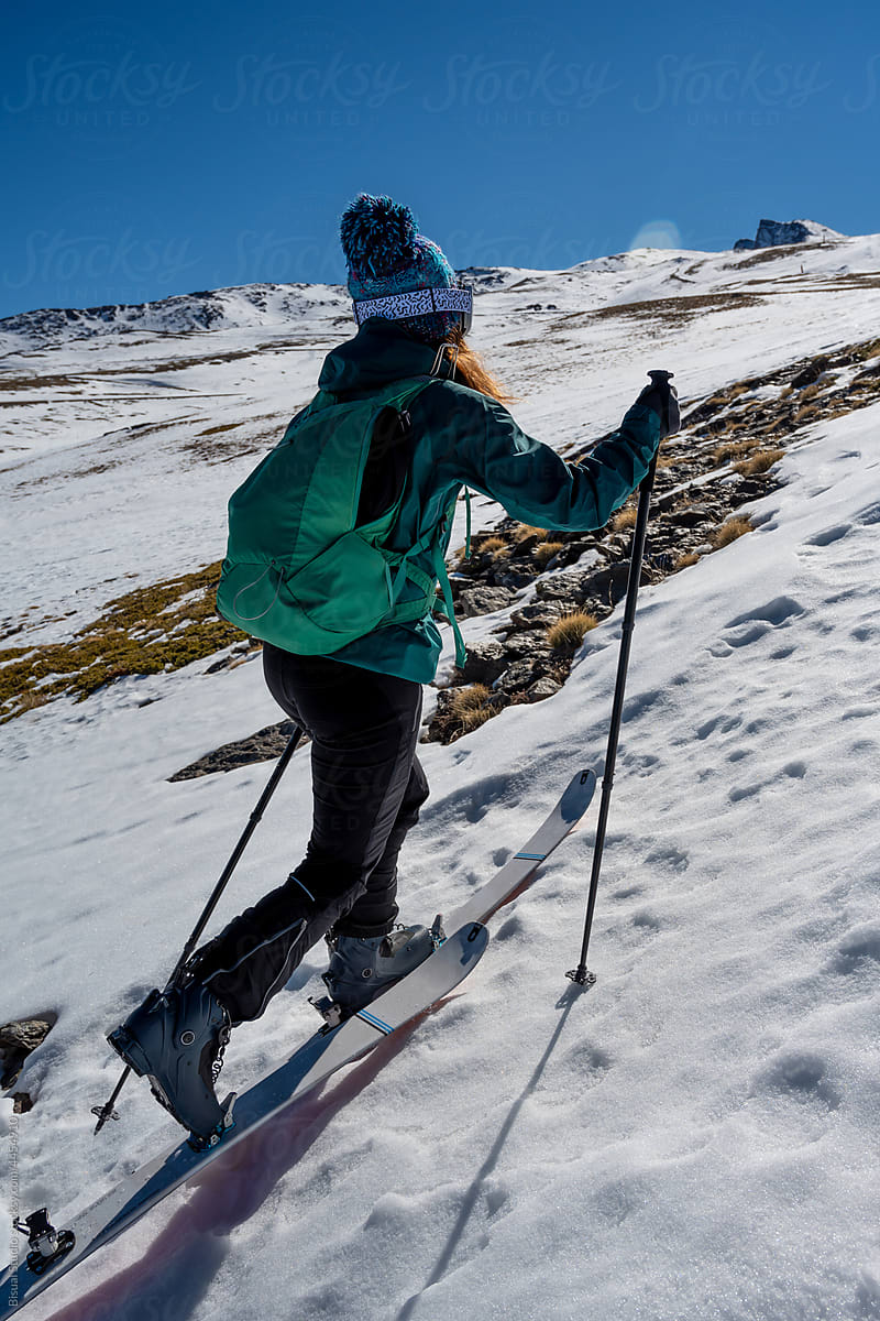 Skier climbing snowy mountain in winter