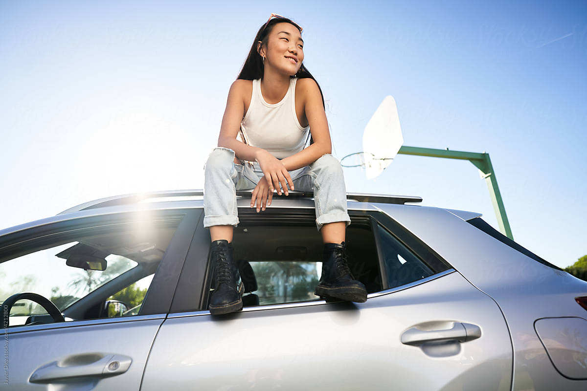 Young woman sitting on SUV car