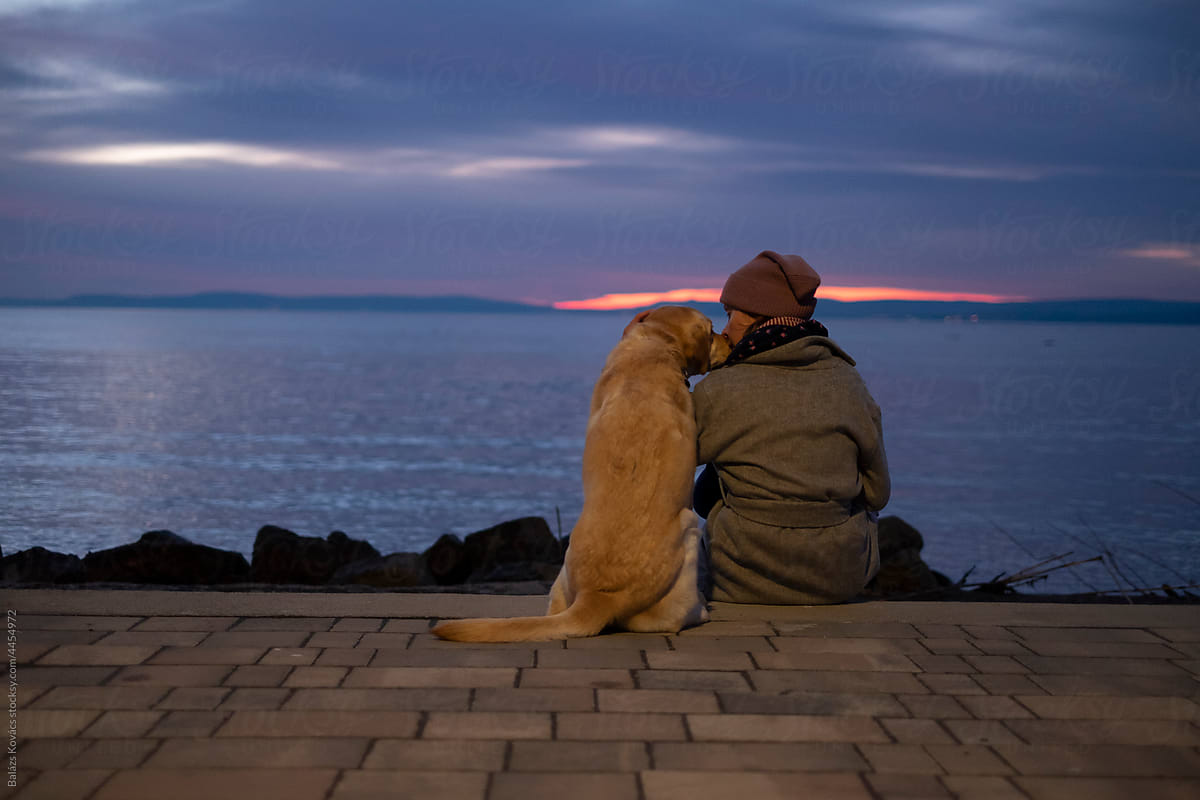 Woman with  a dog after sunset at the lake
