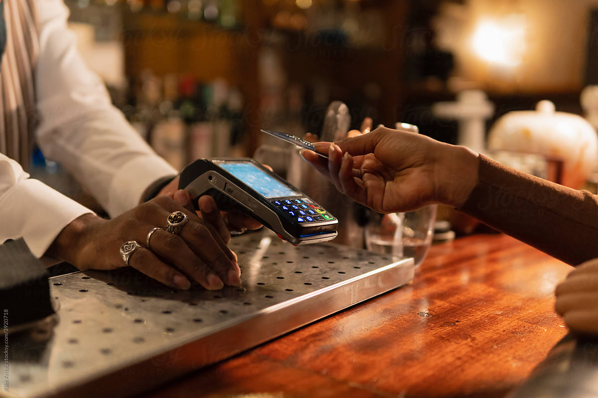 Crop black woman paying for order in bar