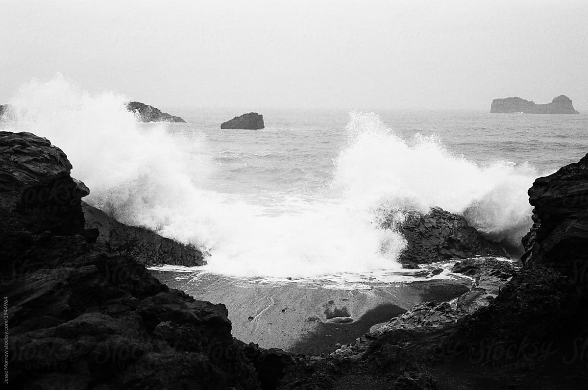 ocean cliff side black sand beach with waves crashing iceland landscape 35mm film black and white