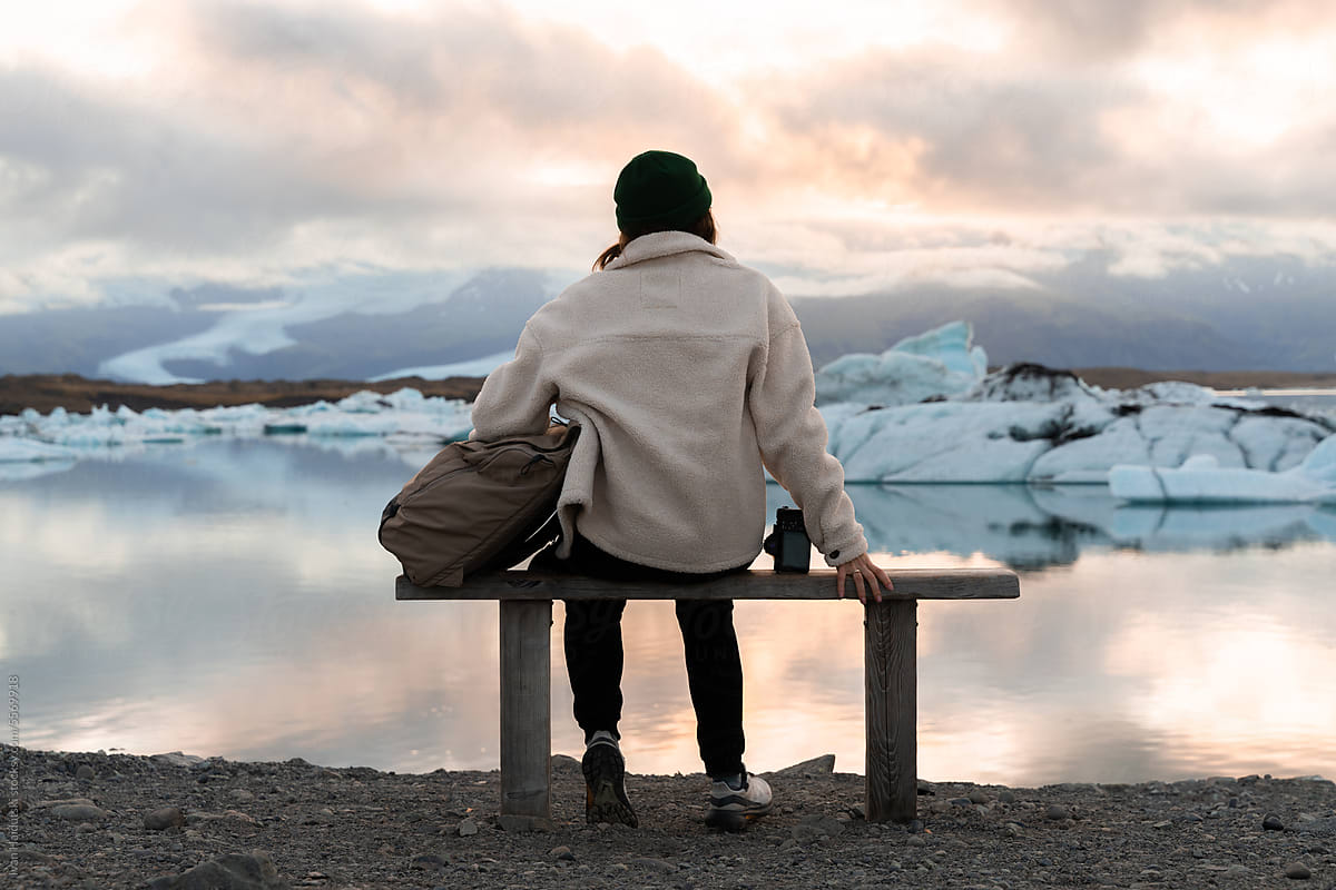 woman form behind on bench enjoying tranquil sunset at glacier lagoon