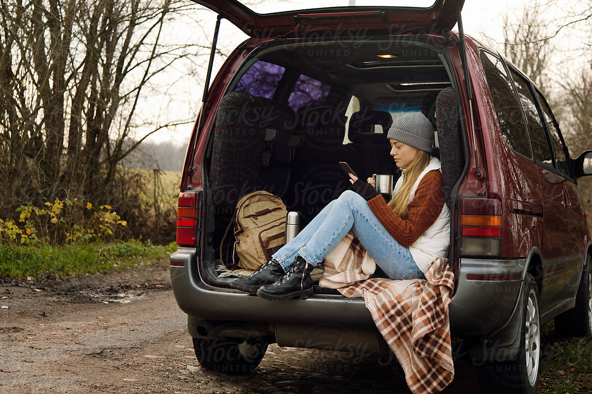 Woman using smartphone in car trunk