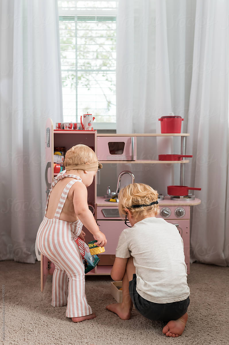 Boy and girl playing with toy kitchen