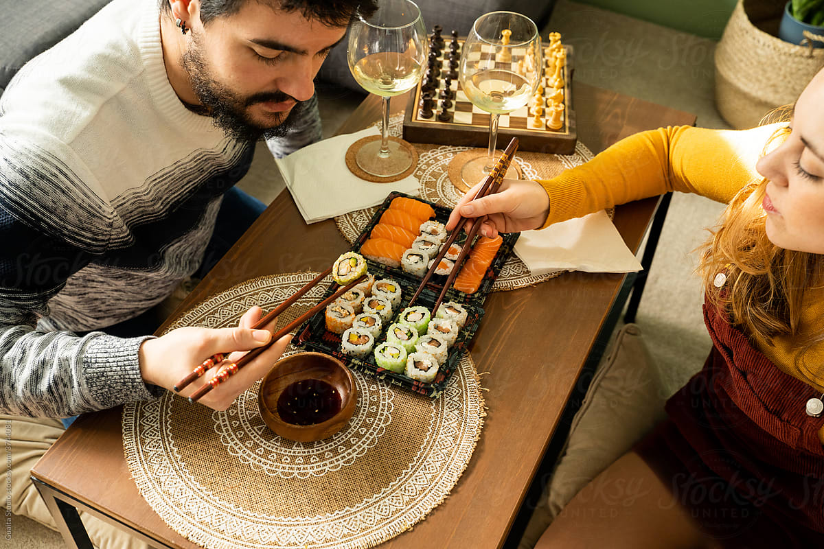 Couple having sushi on coffe table in living room