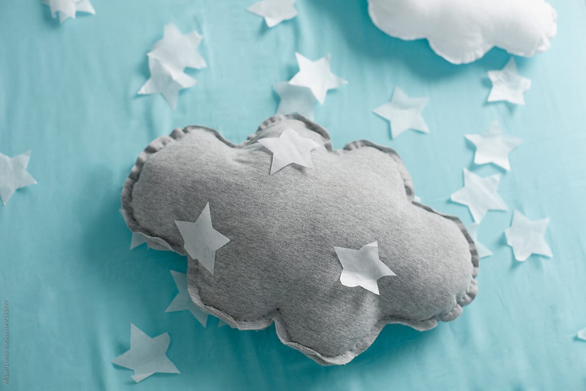 Crafted cloud pillow and paper stars on baby bed