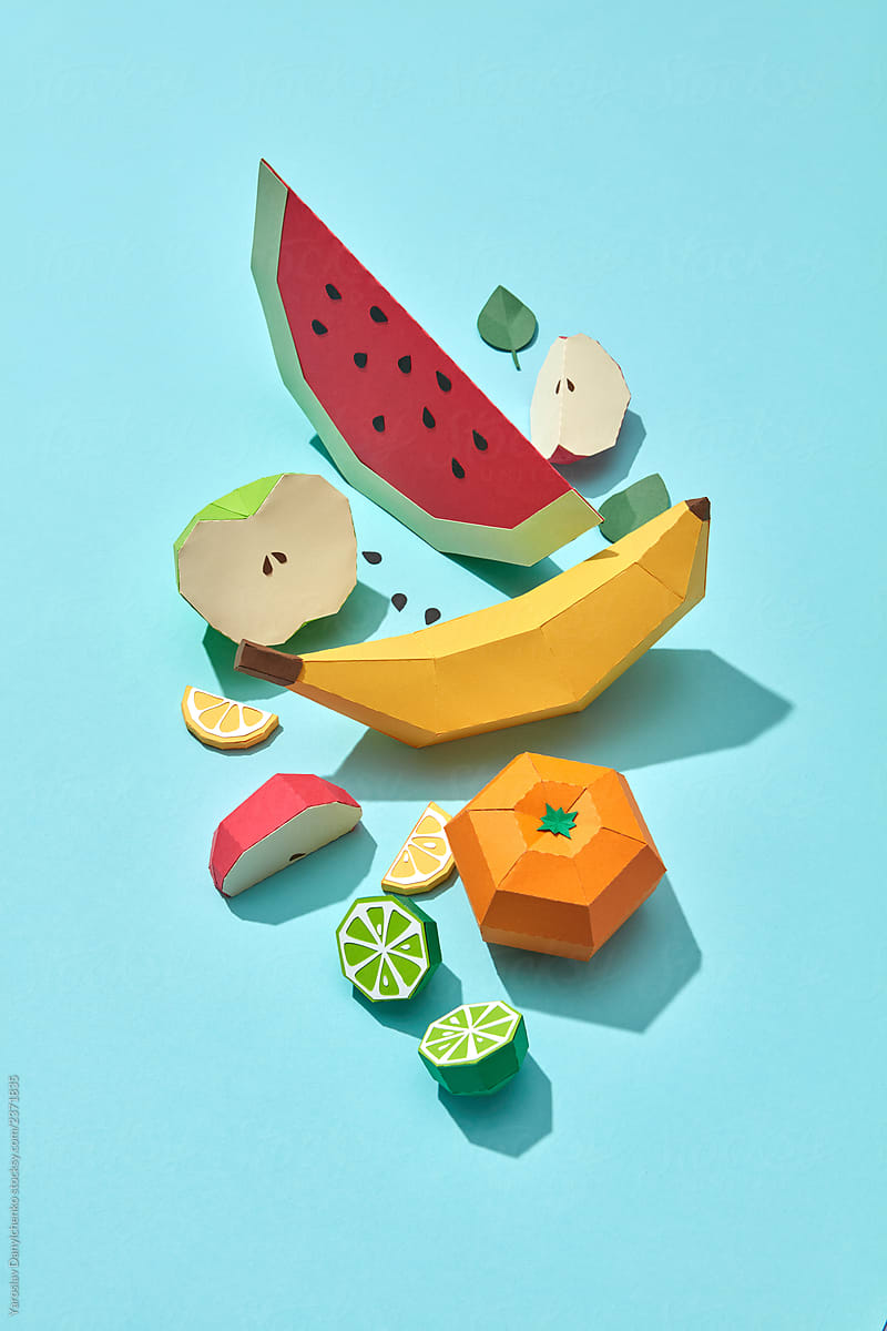 A flat lay of fruit composition of handmade papercraft on a blue background.