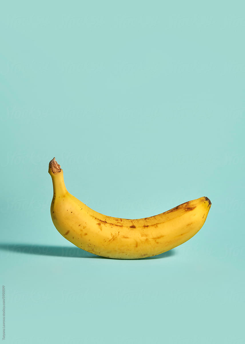 Yellow banana on teal colored background. Art in minimalist style
