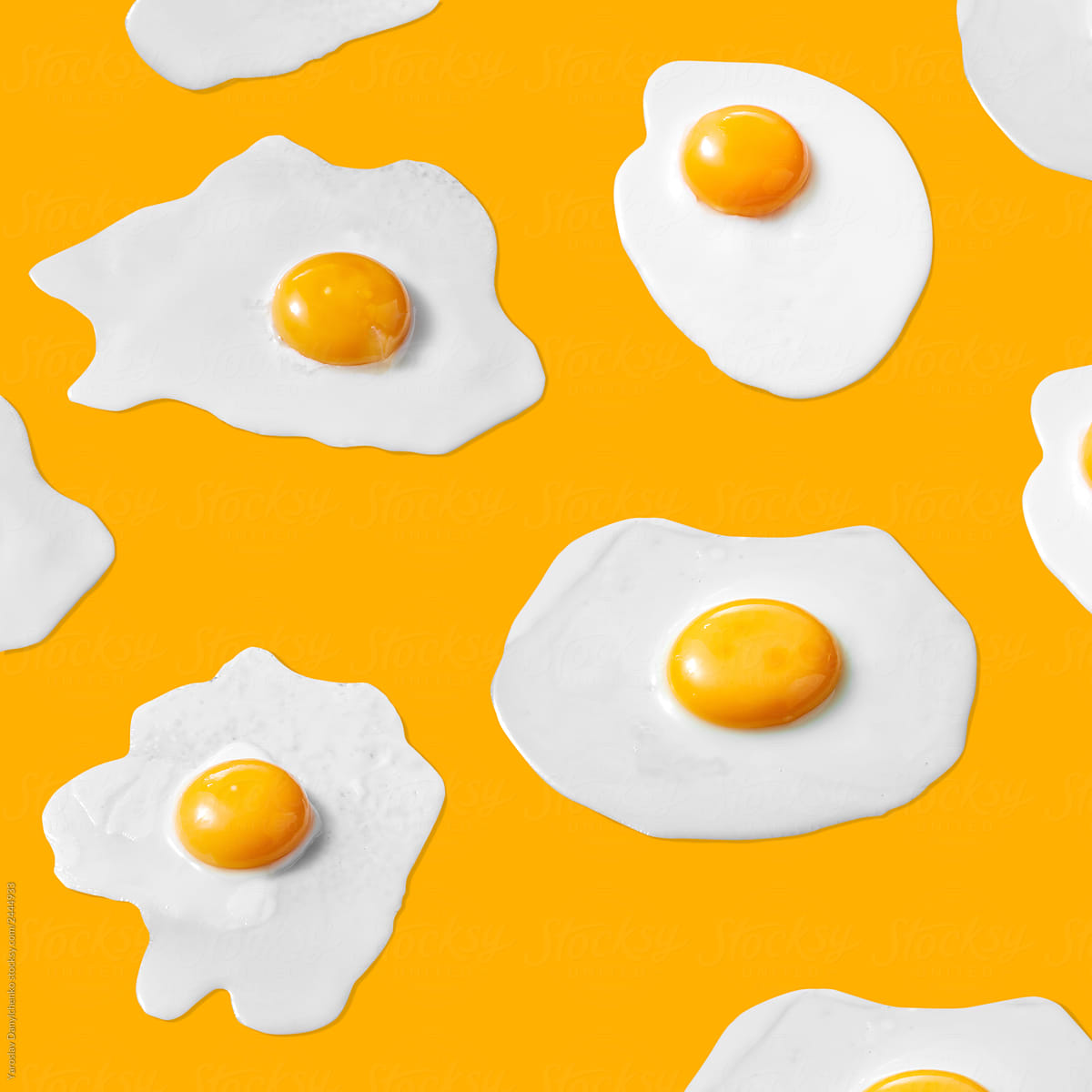 Food pattern from fried eggs with yolks on a yellow background.