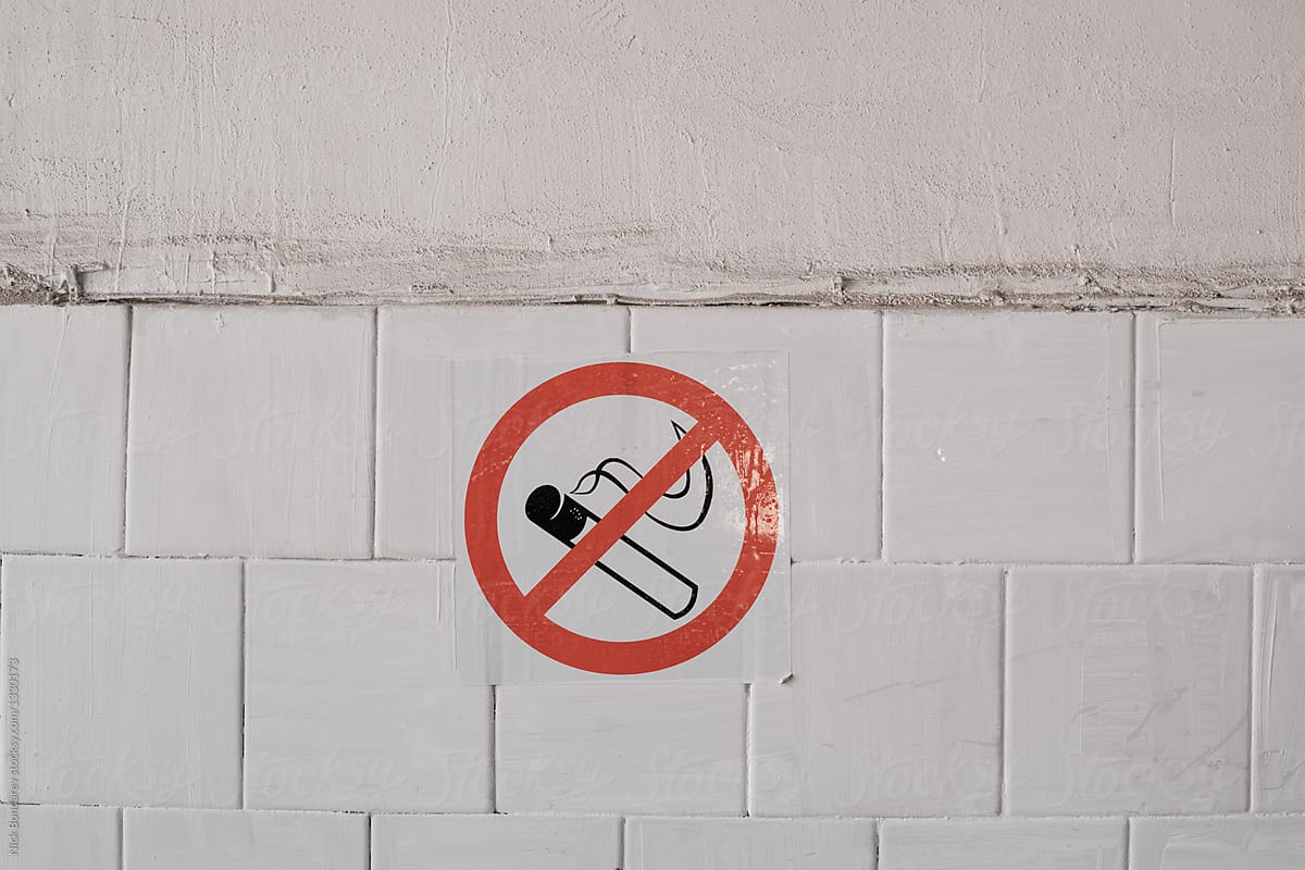 No smoking sign on the tile wall in a toilet