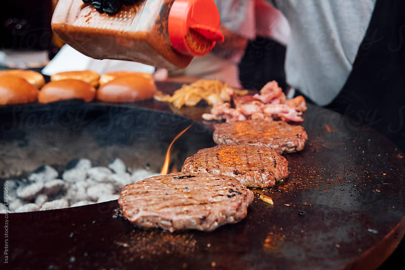 Food: Hamburgers being grilled on an open barbeque fire pit rim