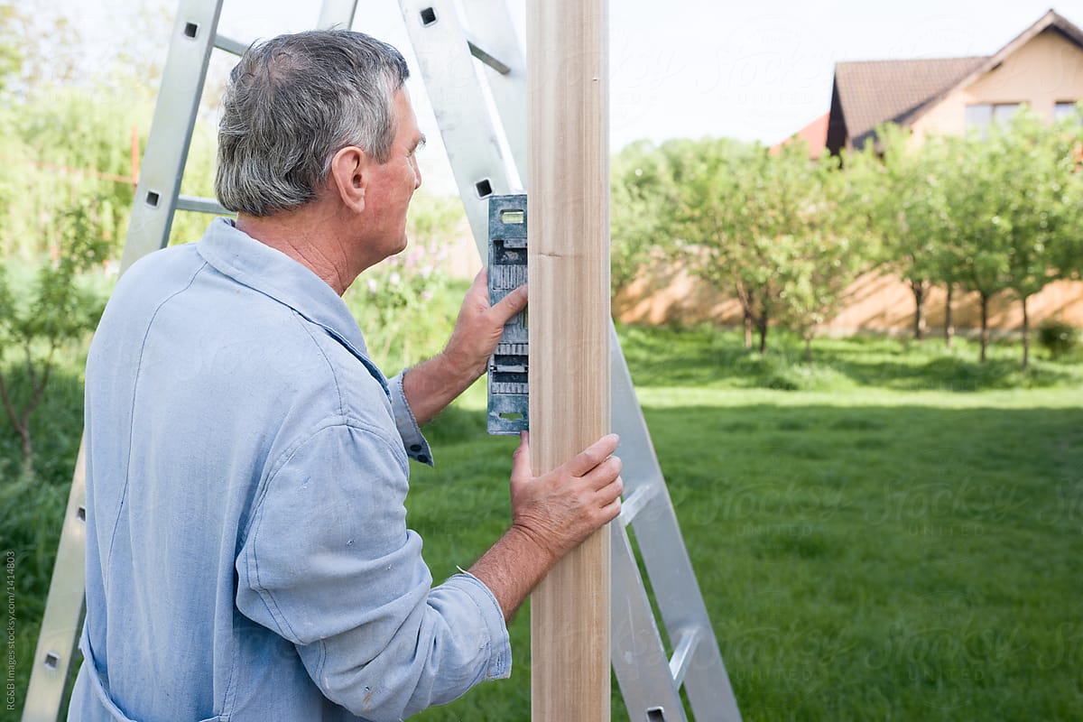 Senior caucasian man inspecting wooden plank for backyard construction