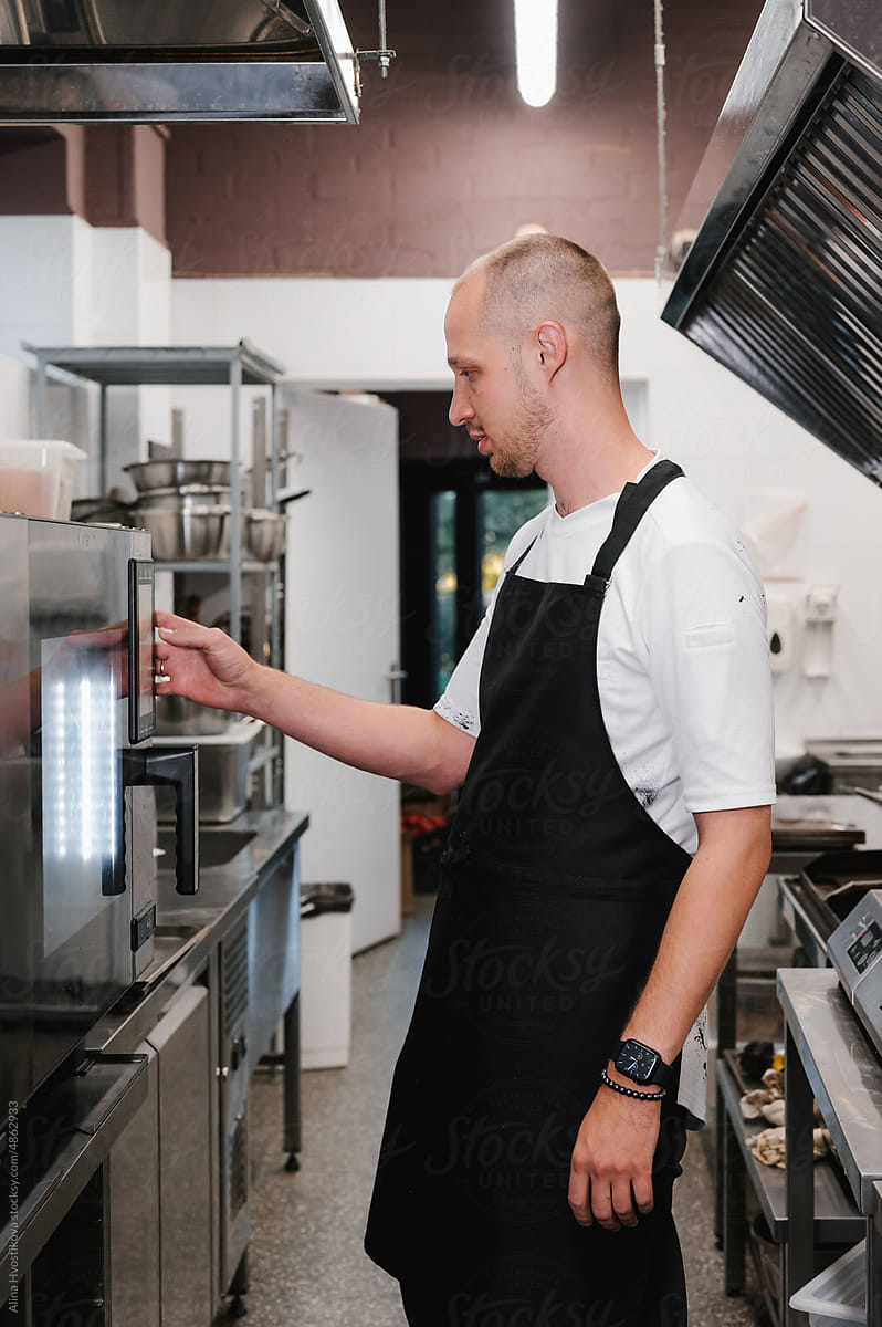 Man setting oven controls in restaurant