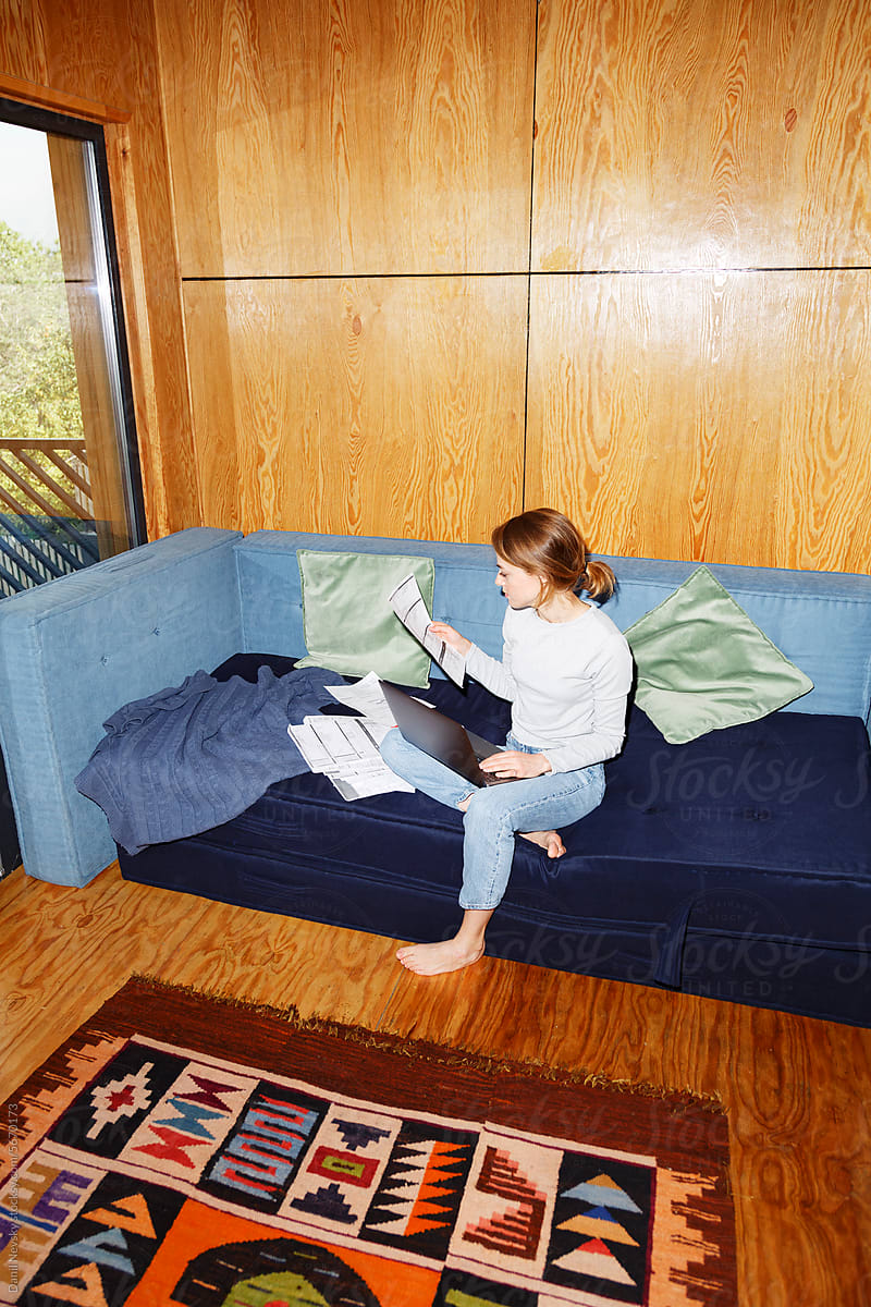 Focused woman examining document on sofa