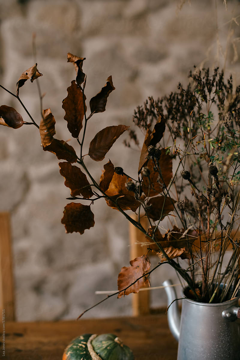 dried fall flower arrangement on table with stone wall