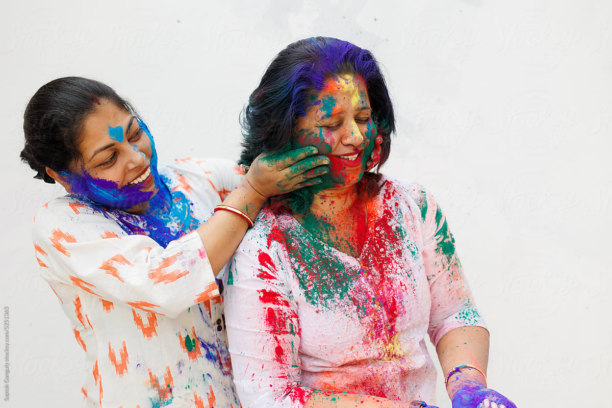 Two middle aged woman playing holi together with color powders