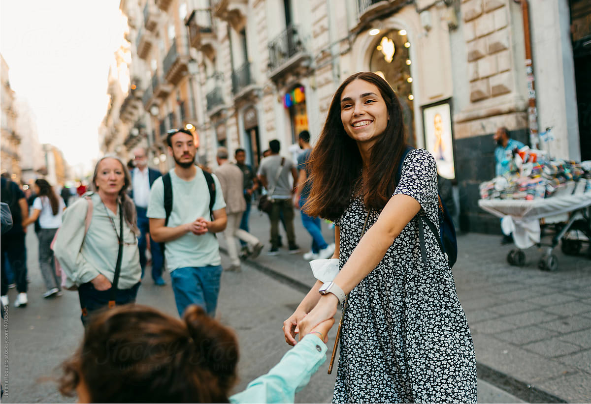 Woman and kid playing in crowded old italian city street smiling