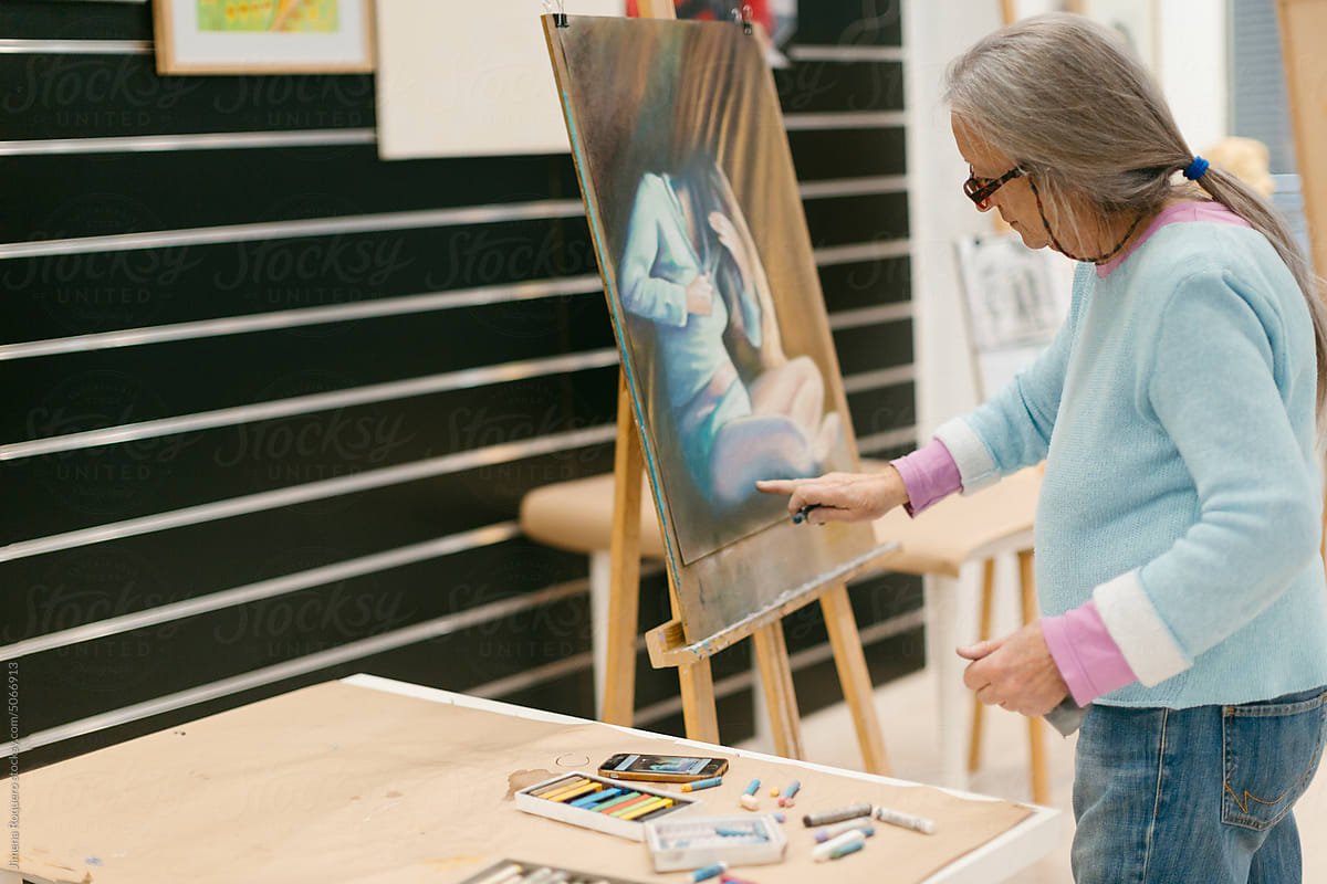 Woman painting with pastel technique in art school studio