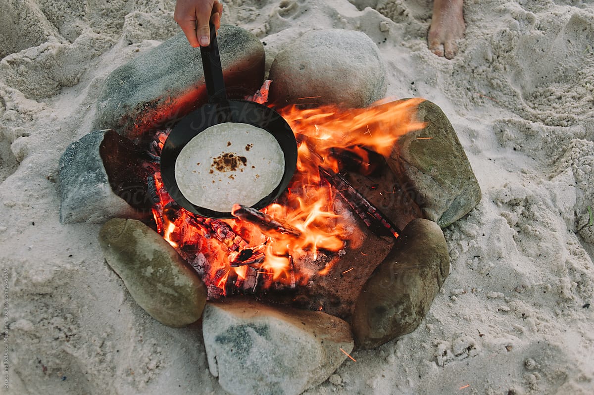 Taco being cooked on an open beach fire
