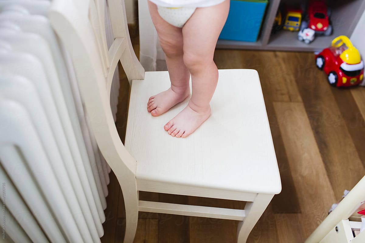 Details of feet of a child standing on the chair