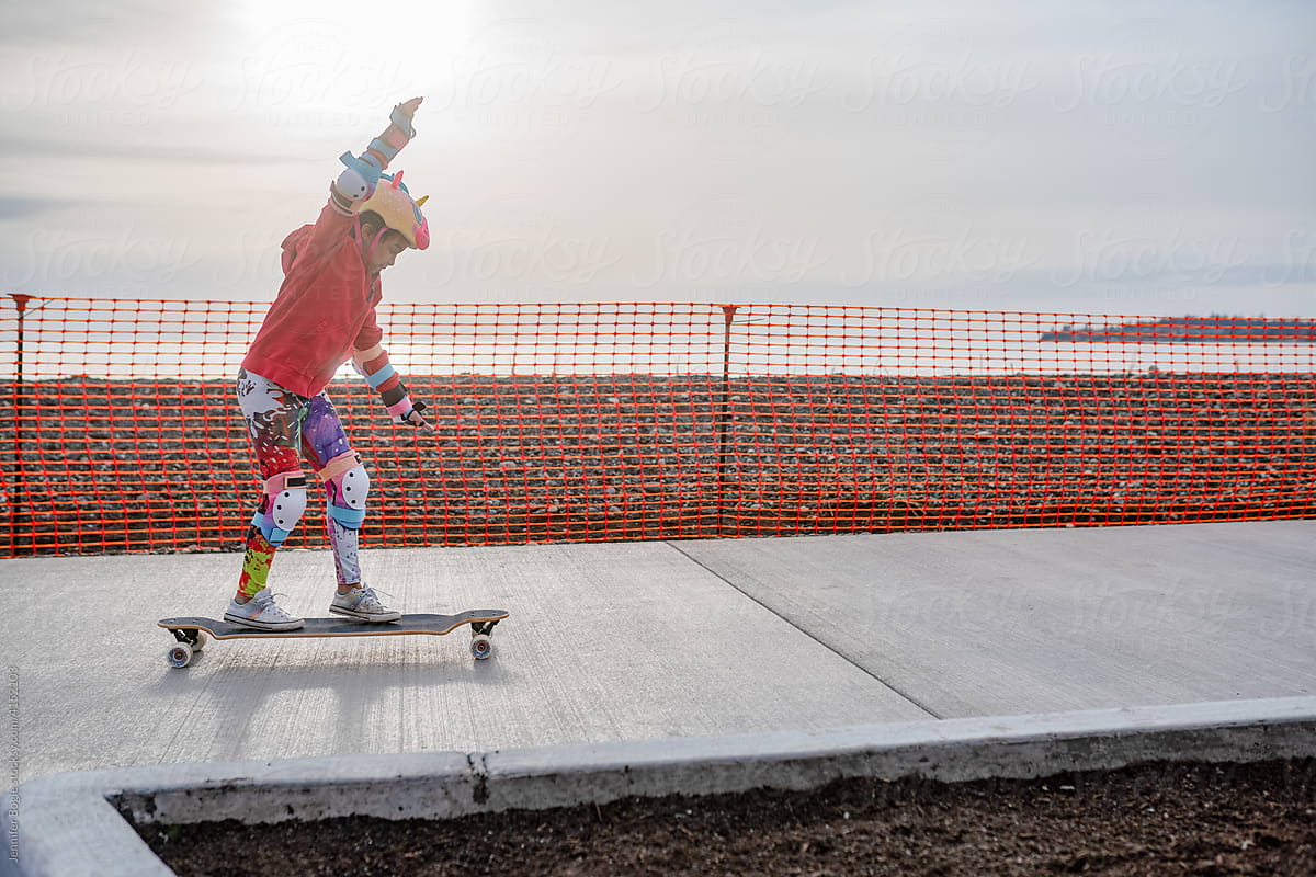 Colorfully dressed girl skateboards on sidewalk