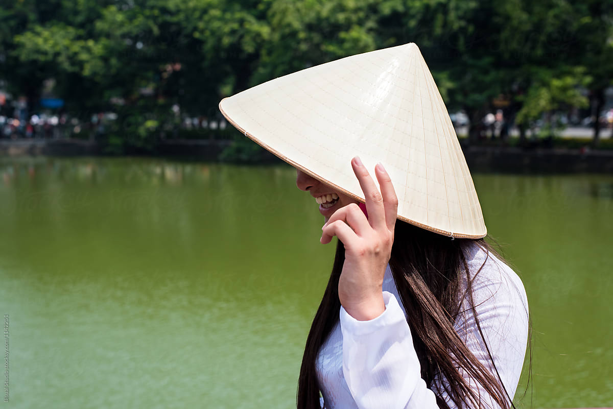 Female in Vietnamese hat near lake