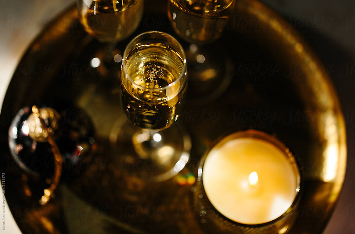 Flutes of sparkling wine with a lit candle and Christmas ornament.