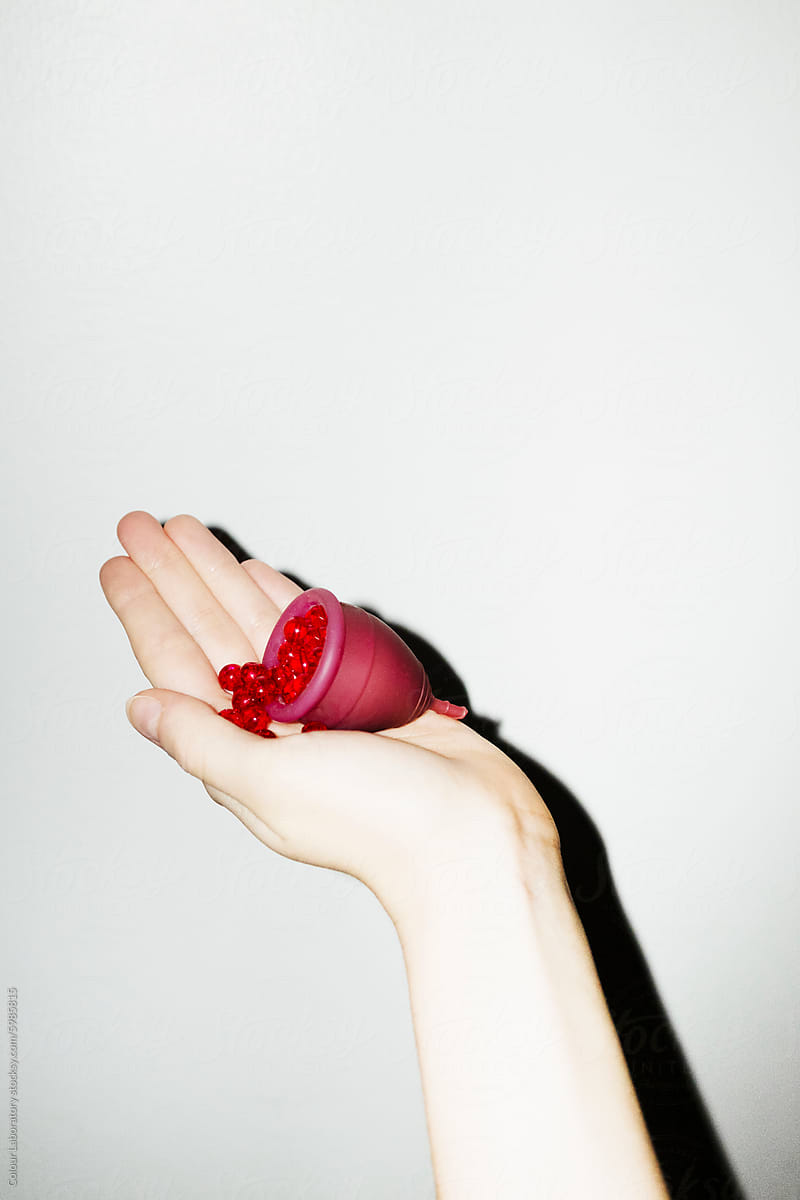 Conceptual photo of period / menstrual cup and red pearls as blood