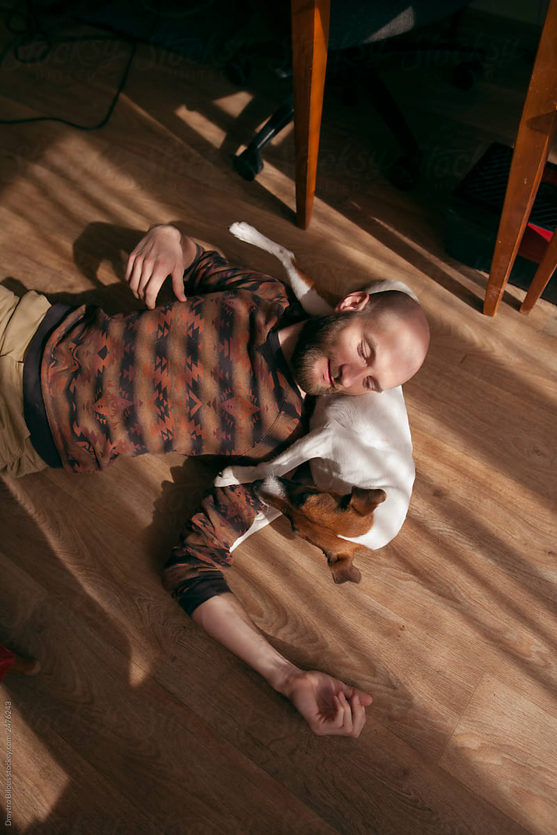 bearded guy lies with his dog on the floor in light and shade