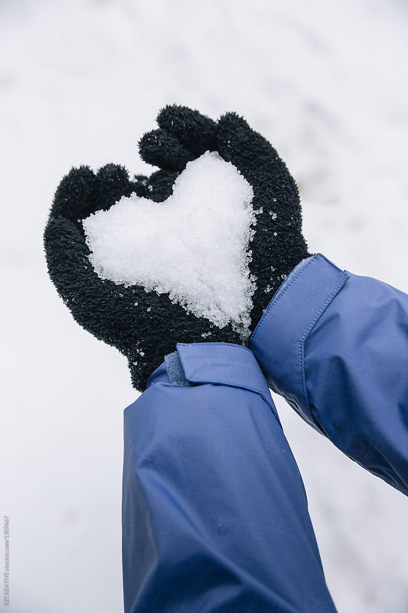 Hands forming a heart shape with snow.