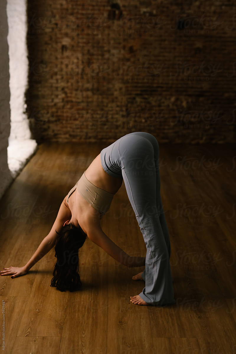 In the morning at a yoga studio, a woman stretches her leg muscles