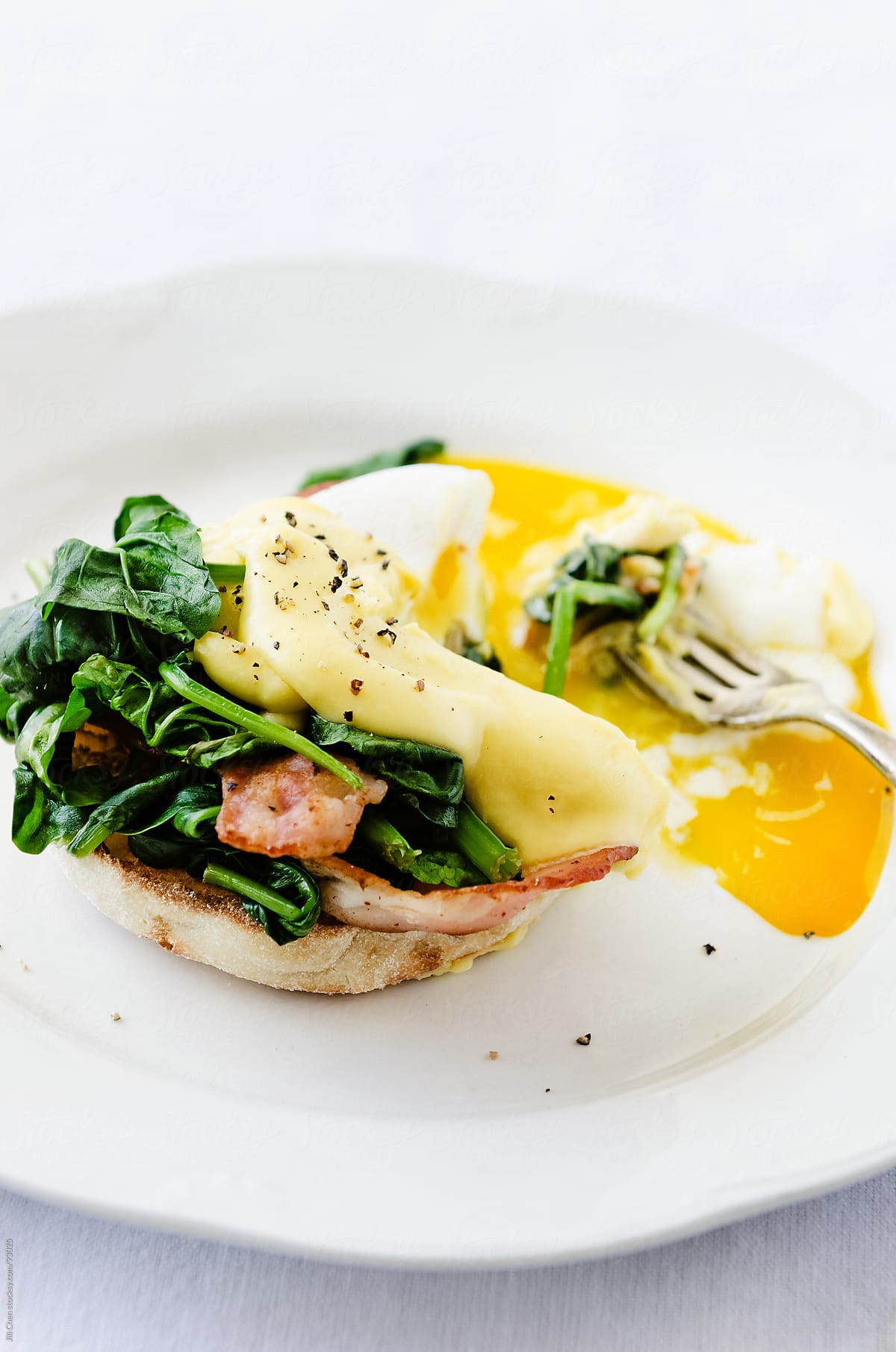 Eggs benedict with hollandaise sauce, spinach and bacon