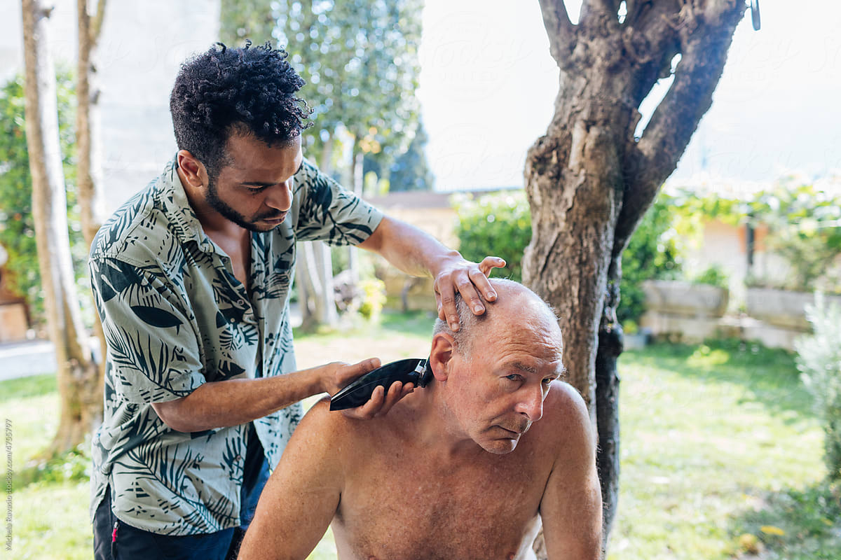 Man adjusting the hair of an older man