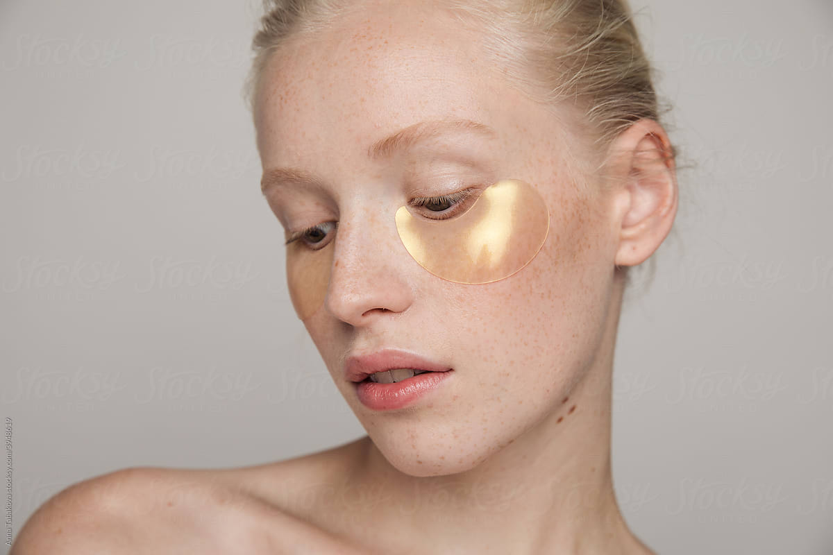 Young freckled model with golden under-eye patches
