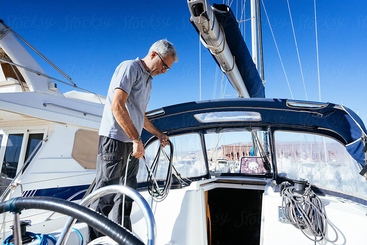 Focused middle aged man tying up boat rope