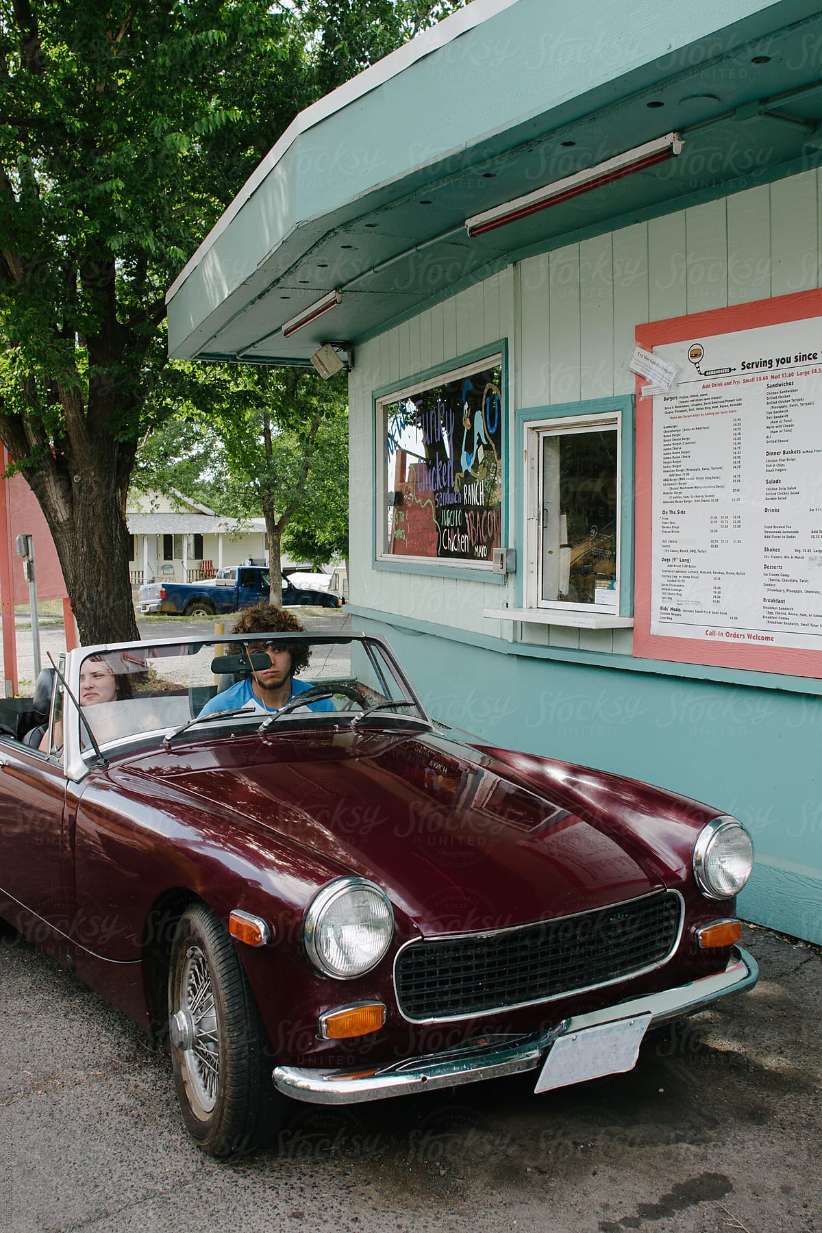 couple sitting in convertible waiting for food a drive thru restaurant